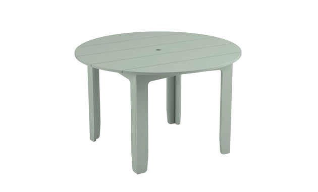 The Mainstay Round Dining Table by Ledge Lounger is light green and round, ideal for outdoor dining. It features four angled legs, a slatted surface, and a built-in umbrella sleeve at its center.