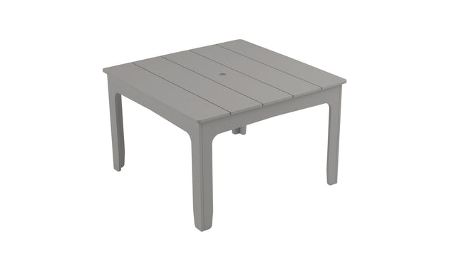 The Mainstay Square Dining Table by Ledge Lounger is light gray with a slatted top and built-in umbrella sleeve. Featuring four straight legs, it presents a simple, modern design ideal for outdoor dining.