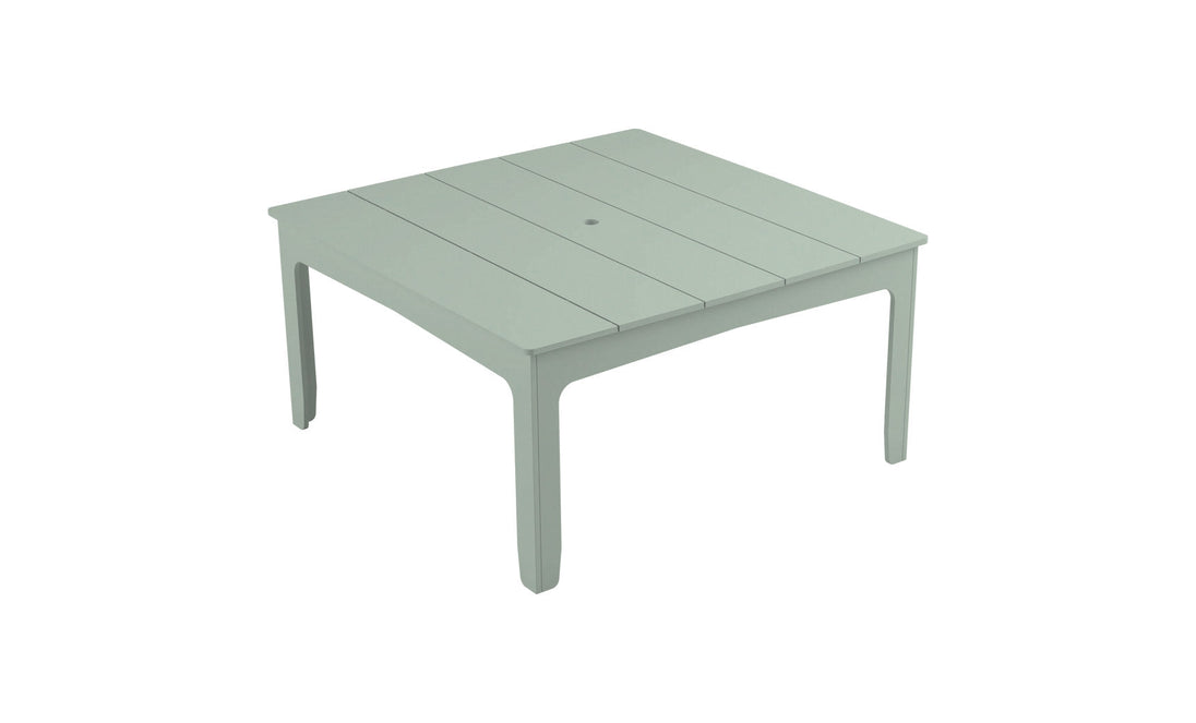 The Mainstay Square Dining Table by Ledge Lounger is a light green, plastic outdoor table with a slatted design, tapered legs, and a central hole with an umbrella sleeve, ideal for alfresco dining.
