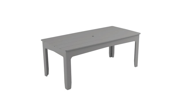 The Mainstay Rectangular Dining Table by Ledge Lounger is a light gray table with a slatted top and straight legs, ideal for outdoor meals. It has a central hole with an umbrella sleeve for shade. Set against a white backdrop, its sleek design stands out.