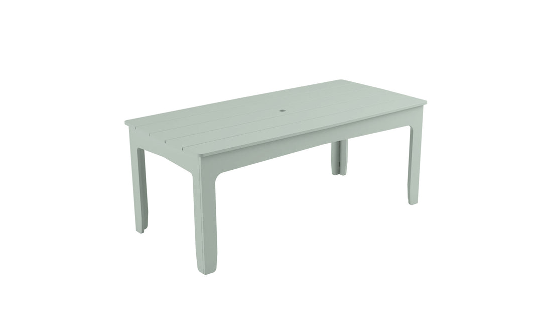 The Mainstay Rectangular Dining Table by Ledge Lounger is light green with a slatted top and sturdy four-leg design. It has a central hole for an umbrella sleeve, perfect for outdoor dining, and is set against a plain white background.