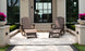 Two Legacy Adirondack by Ledge Lounger chairs with footrests sit on a patio in front of a modern building, ideal for gatherings. Behind them are large windows and stairs, while planters with purple flowers and trimmed hedges add to the inviting outdoor setup.