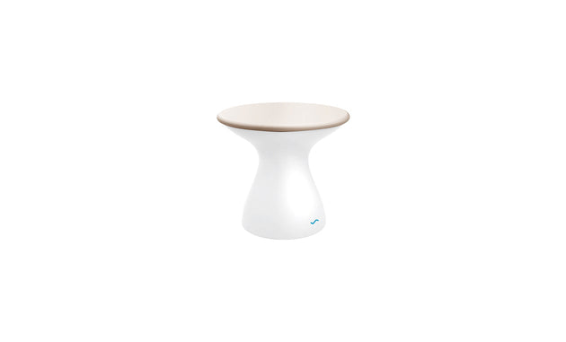 The Autograph Standard Side Table by Ledge Lounger showcases a modern hourglass shape with a white glossy base and beige flat top, ideal as an outdoor side table. Its sleek design on a plain white background is finished with a subtle blue logo at the bottom.