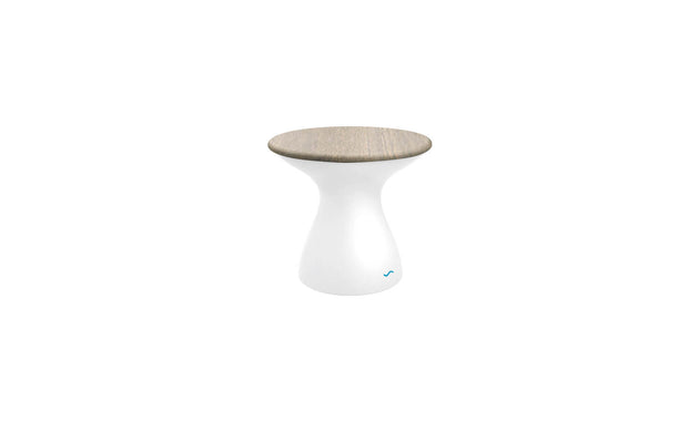 The Autograph Standard Side Table by Ledge Lounger features a smooth, white hourglass-shaped base and a flat, light wood top. This modern minimalist stool doubles as an outdoor side table, perfect for contemporary flair and poolside storage needs.