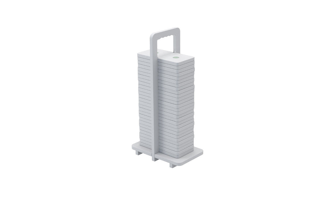 The Dominoes from Ledge Lounger are stacked white square plates with rounded edges, arranged vertically on a holder with a top handle. Their minimalist design resembles giant dominos, showcasing neat uniformity and high-quality craftsmanship.
