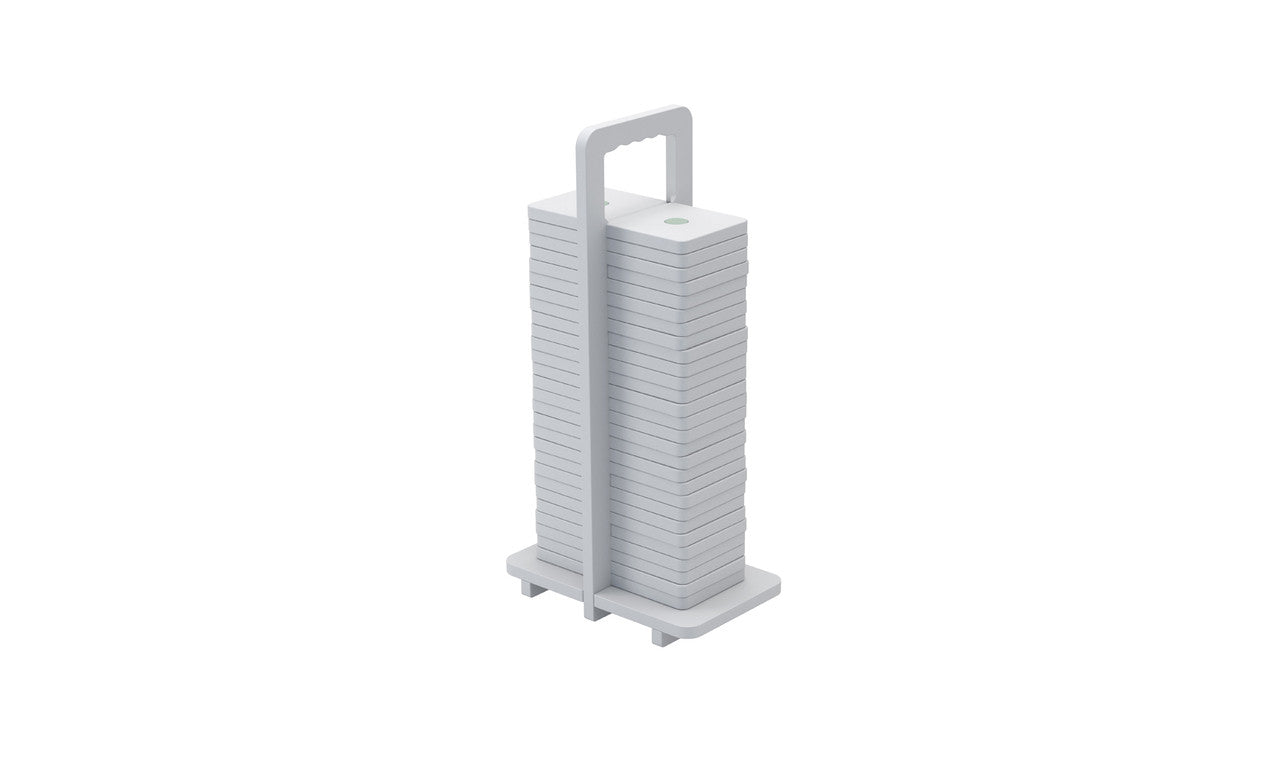 The Dominoes from Ledge Lounger are stacked white square plates with rounded edges, arranged vertically on a holder with a top handle. Their minimalist design resembles giant dominos, showcasing neat uniformity and high-quality craftsmanship.