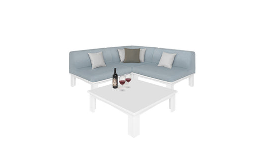 The Mainstay Sectional 4 Piece Diamond from Ledge Lounger in light blue forms a cozy corner with four cushions around a white square coffee table. The table features a wine bottle and two filled glasses, all set against a plain white background.
