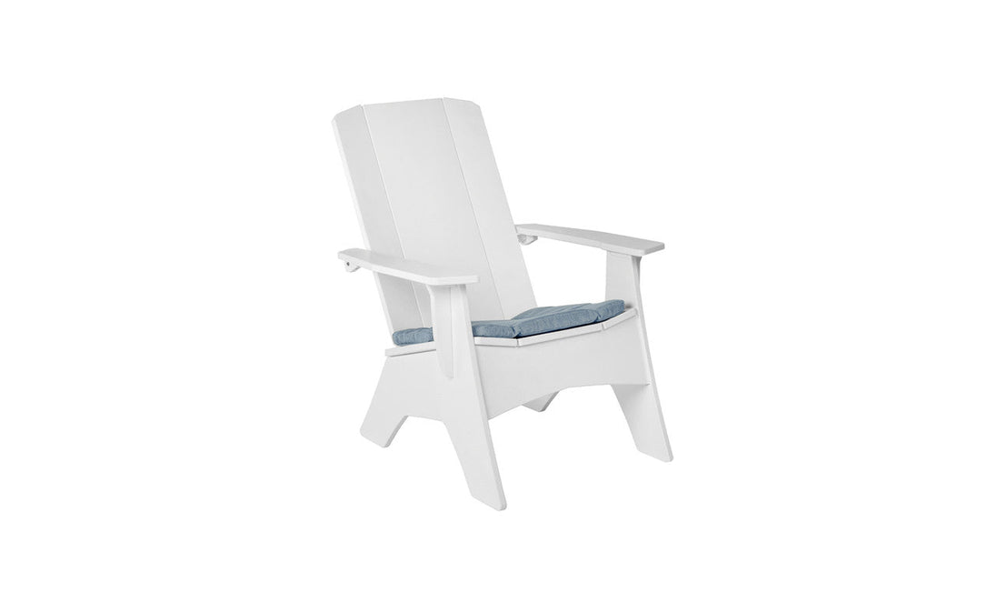 A white wooden Adirondack chair features wide armrests and a slightly reclined backrest. It includes a Mainstay Adirondack Seat Cushion by Ledge Lounger in blue, making it an ideal outdoor seat. The setup sits against a plain white background.