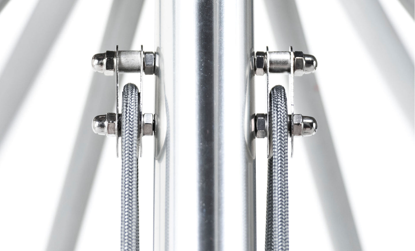 A close-up of a symmetrical metal structure with fiberglass ribs and vertical cables flanking a central pole mirrors the industrial aesthetic of an Essential Fiberglass Umbrella - 10 Square Pulley by Ledge Lounger against a bright white backdrop.