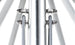 Close-up of a metallic structure with tension cables attached to bolts on either side of a central pole, resembling the robust design of the Ledge Lounger Essential Fiberglass Umbrella - 8.5 Rectangle Pulley. The blurred background emphasizes the shiny industrial components.