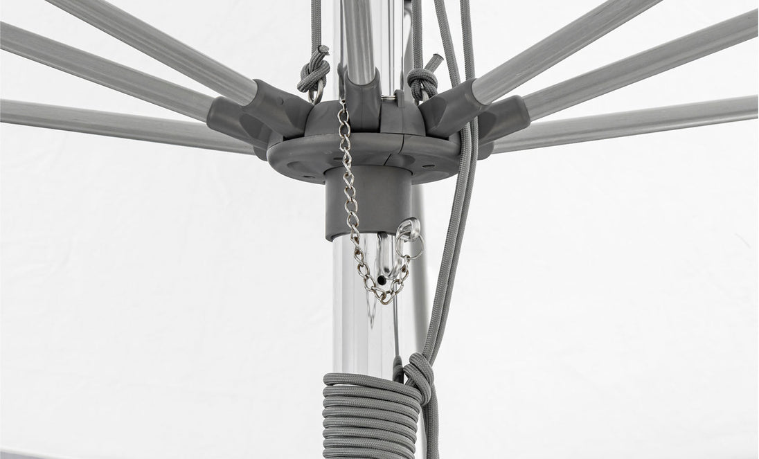The Essential Fiberglass Umbrella - 8.5 Rectangle Pulley by Ledge Lounger features a corrosion-resistant gray metal mechanism with visible ribs, a pulley system with a chain, and a coiled rope. The durable white fabric complements its robust construction designed to withstand the elements.