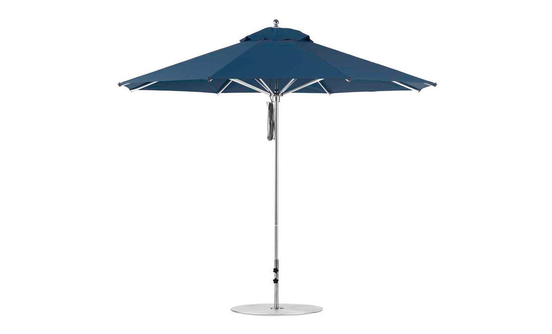 The Ledge Lounger Premier Aluminum Umbrella - 11 Octagon Pulley features a blue canopy and metal pole, showcasing its round shape. Made from marine-grade fabrics with multiple ribs, its designed to be wind resistant for outdoor use.