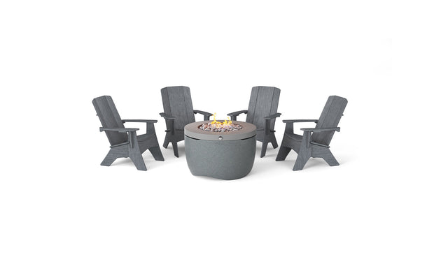 The Halo Aglow Bundle by Ledge Lounger features four dark gray Adirondack chairs around a round gray outdoor gas fire pit, embellished with small stones and a gentle central flame, set against a plain white background.