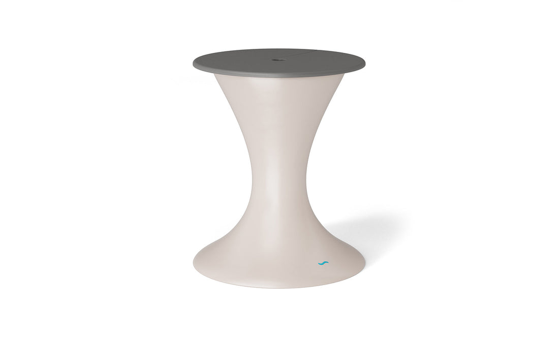 The Autograph Umbrella Stand Ice Bin by Ledge Lounger features a modern hourglass shape with a cream base and dark gray circular seat. This sleek design serves both as an outdoor table and a stool, ideal for contemporary interiors.