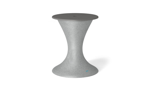 The Ledge Lounger Autograph Umbrella Stand Ice Bin is a chic hourglass-shaped outdoor table with a textured gray finish, tapering wide at the base and top. The slightly darker gray flat top has a central detail ideal for an umbrella stand.