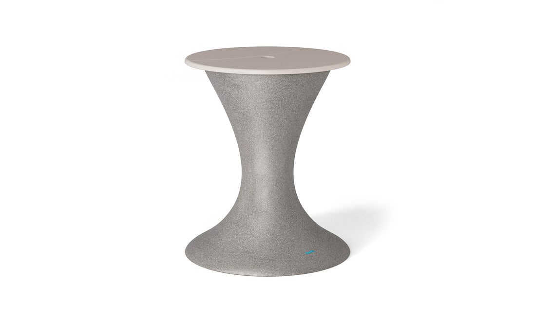 The Autograph Umbrella Stand Ice Bin by Ledge Lounger, featuring a tall, hourglass design with a gray speckled body and light beige top, serves as an elegant outdoor table or stool to enhance any patio setup.