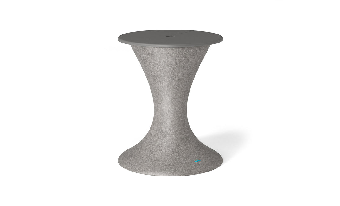 The Ledge Lounger Autograph Umbrella Stand Ice Bin is a sleek, modern, gray hourglass-shaped stand with a smooth wide base and circular top. It features a center hole, making it versatile as both an outdoor table that accommodates an umbrella stand and doubles as an ice bin.