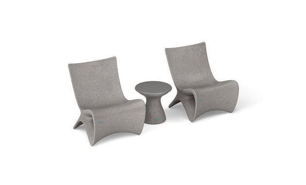 Two Classic Luxury In-Pool Chair Duo pieces from Ledge Lounger, in a modern gray hue with curved backs and seats, are placed beside a matching round side table. The set boasts a minimalist, sculptural design.