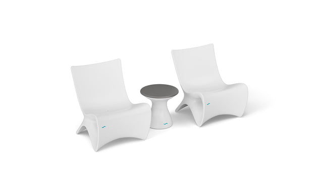The Classic Luxury In-Pool Chair Duo by Ledge Lounger features two modern, white lounge chairs with curved backs, paired with a small round side table with a dark gray top, elegantly displayed on a plain white background.