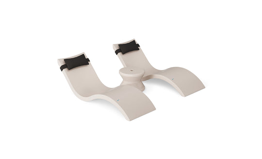 The Ledge Lounger Signature Chaise Headrest Pillow and Side Table In-Pool Set features two modern beige loungers with headrest pillows connected by a round table, creating the ideal poolside setup against a white background.