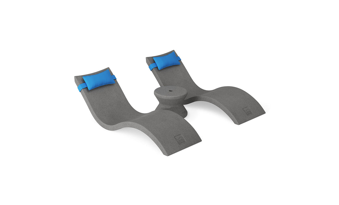 The Ledge Lounger Signature Chaise Headrest Pillow and Side Table In-Pool Set features curved gray lounges with blue headrests and a round table—ideal for creating a relaxing poolside retreat or enhancing your outdoor paradise.