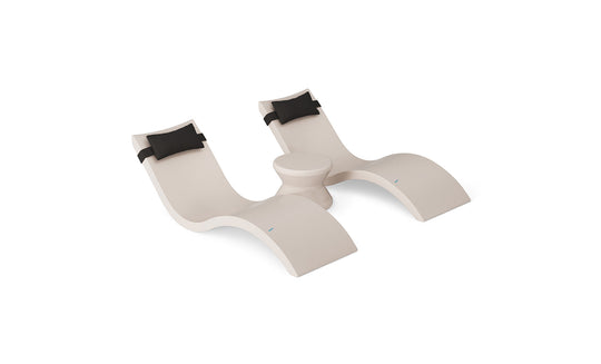 The Ledge Lounger Signature Chaise Headrest Pillow and Side Table In-Pool Set features modern beige double wave-shaped chaise loungers with black headrest pillows and a round table between them, set against a white background.