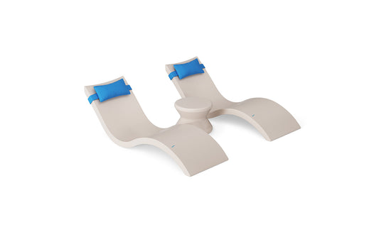 The Ledge Lounger Signature Chaise Headrest Pillow and Side Table In-Pool Set features two modern beige chaise loungers with blue headrest pillows and a round side table, all displayed against a white background.