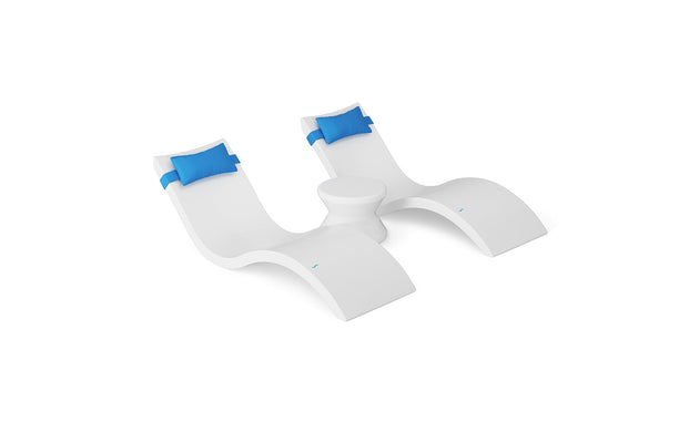 The Ledge Lounger Signature Chaise Headrest Pillow and Side Table In-Pool Set features two modern white chaise loungers with blue headrests, joined by a round side table—perfect poolside seating for your outdoor paradise against a white background.