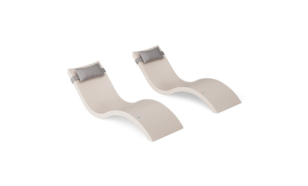 The Ledge Lounger Signature Chaise and Headrest Pillow In-Pool Set includes two modern beige wave-shaped chaises with gray pillows, side by side on a white background—ideal for stylish outdoor furniture.