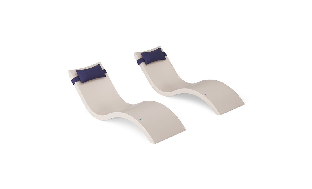 The Ledge Lounger Signature Chaise and Headrest Pillow In-Pool Set features two modern beige wavy lounge chairs with dark blue headrest pillows, placed side by side on a white background—ideal for stylish outdoor spaces.