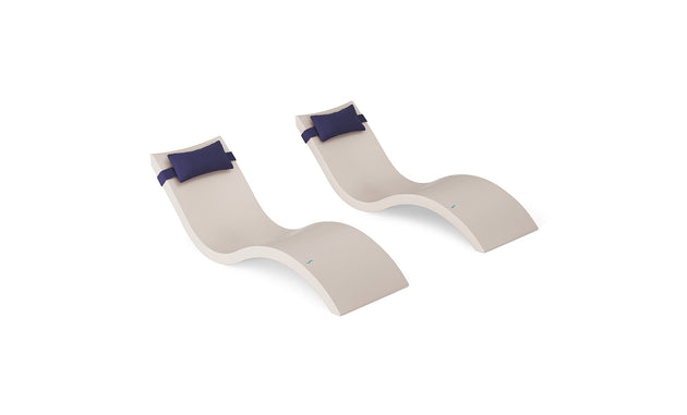 The Ledge Lounger Signature Chaise and Headrest Pillow In-Pool Set features two modern beige wavy lounge chairs with dark blue headrest pillows, placed side by side on a white background—ideal for stylish outdoor spaces.
