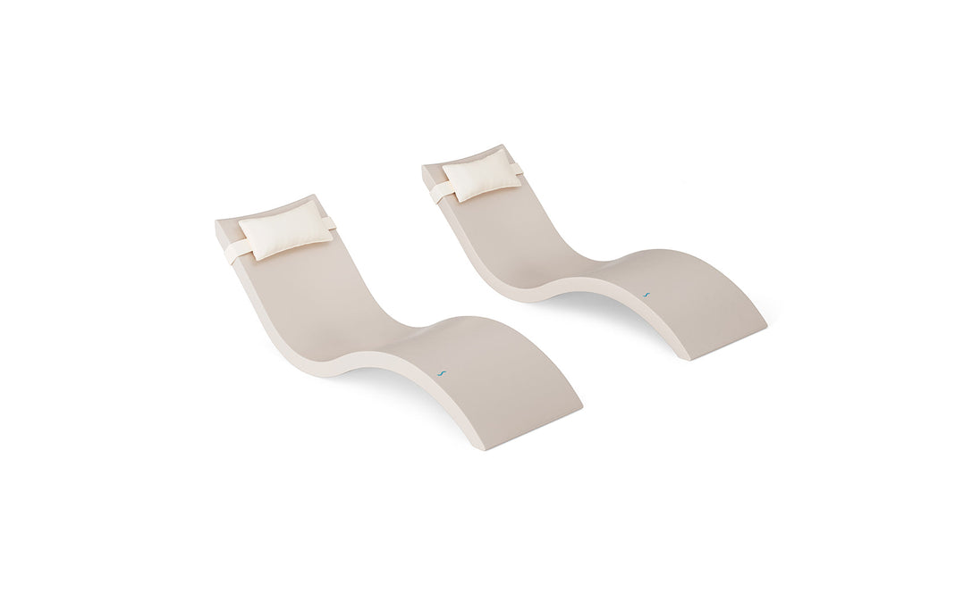 The Ledge Lounger Signature Chaise and Headrest Pillow In-Pool Set features two modern beige, wave-shaped lounges with white headrests, placed side by side, perfect for stylish outdoor or poolside settings.
