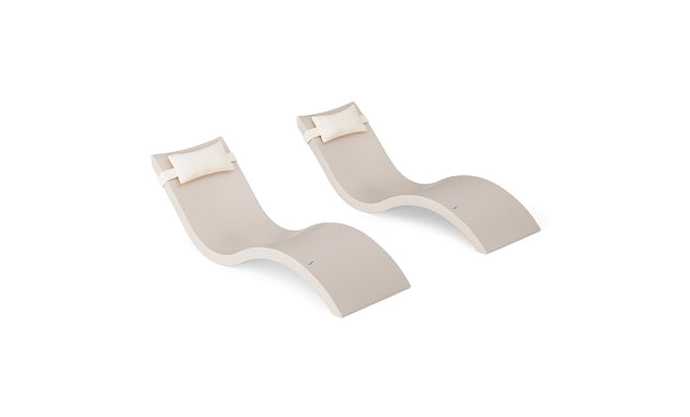 The Ledge Lounger Signature Chaise and Headrest Pillow In-Pool Set features two modern beige, wave-shaped lounges with white headrests, placed side by side, perfect for stylish outdoor or poolside settings.