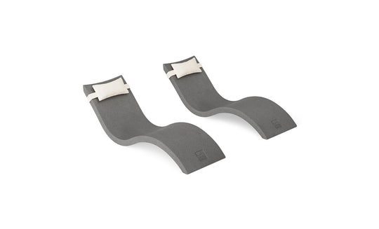 The Signature Chaise and Headrest Pillow In-Pool Set by Ledge Lounger features two modern gray chaise lounges with curvy shapes and plush white pillows, creating a perfect outdoor retreat, shown on a white background.