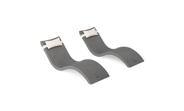 The Signature Chaise and Headrest Pillow In-Pool Set by Ledge Lounger features two modern gray chaise lounges with curvy shapes and plush white pillows, creating a perfect outdoor retreat, shown on a white background.
