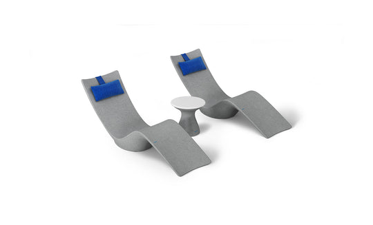 The Resort Luxury Outdoor Paradise In-Pool Furniture Bundle by Ledge Lounger includes two modern, curved gray chaise loungers with attached blue cushions flanking a small round white table, ideal for poolside relaxation against a plain white background.