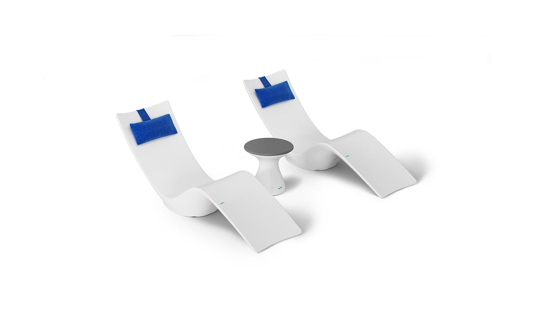 The Resort Luxury Outdoor Paradise In-Pool Furniture Bundle by Ledge Lounger includes two white chaise loungers with blue headrests, ideal for poolside relaxation, and a small round white table with a dark top set against a crisp white background.