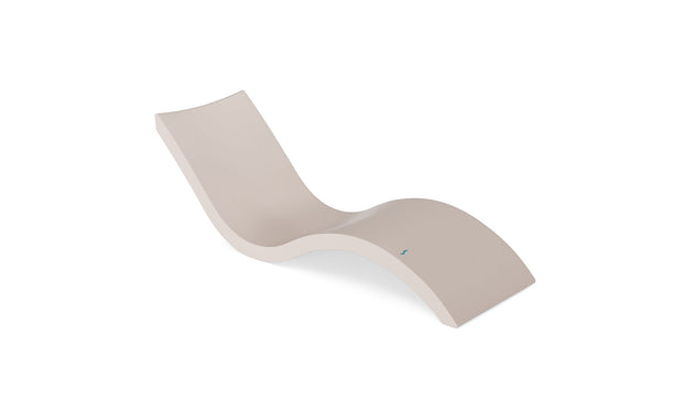 The Signature Chaise by Ledge Lounger features a modern, minimalist beige design with smooth curves that provide wave-like ergonomic comfort. Ideal for indoor or outdoor pool relaxation, it seamlessly blends style and functionality.