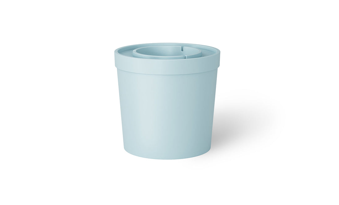 The Signature Ice Basin by Ledge Lounger is a light blue, cylindrical plastic container with a lid. The lid includes a central recessed area and a small slit for easy pouring, casting a subtle shadow on the white background.