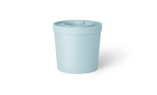 The Signature Ice Basin by Ledge Lounger is a light blue, cylindrical plastic container with a lid. The lid includes a central recessed area and a small slit for easy pouring, casting a subtle shadow on the white background.