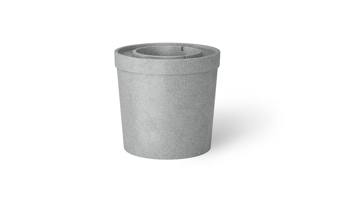 The Signature Ice Basin by Ledge Lounger is a sleek, gray cylinder with a flat, raised lid seen from an angle. Its minimalist design features a smooth finish and uniform color, with an indented line on top hinting at a removable lid or inner component.