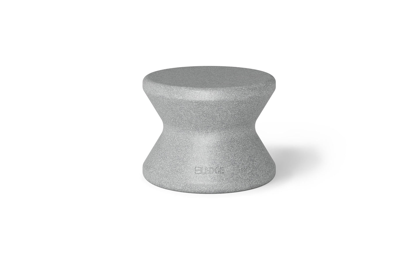 The Signature Standard Side Table by Ledge Lounger is a gray hourglass-shaped stool with a textured surface and smooth, curved design, perfect for in-pool use. The name BLØK is subtly engraved near the base, set against a plain white background.
