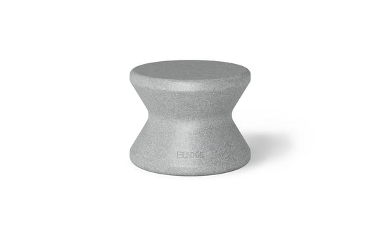 The Signature Standard Side Table by Ledge Lounger is a gray hourglass-shaped stool with a textured surface and smooth, curved design, perfect for in-pool use. The name BLØK is subtly engraved near the base, set against a plain white background.