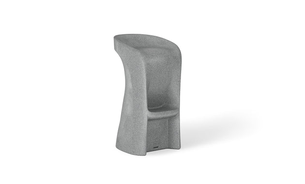Introducing the Signature Barstool Bar Height by Ledge Lounger: a modern minimalist gray stool with a high backrest, cylindrical form, and stone-like texture. Its widened base and integrated footrest ensure support, while the curved seat is perfect for poolside seating during outdoor entertaining.