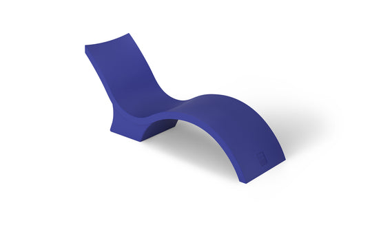 The Signature Chaise Deep by Ledge Lounger is a sleek, modern lounge chair with a minimalist wave design in bold blue. Its smooth, curved form creates a contemporary look, perfect for relaxing on the tanning ledge or adding flair against a plain white background.