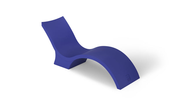 The Signature Chaise Deep by Ledge Lounger is a sleek, modern lounge chair with a minimalist wave design in bold blue. Its smooth, curved form creates a contemporary look, perfect for relaxing on the tanning ledge or adding flair against a plain white background.