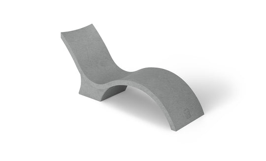 The Signature Chaise Deep by Ledge Lounger is a minimalist grey lounge chair with a wavy, modern design like a chaise lounge, featuring smooth surfaces and continuous curves for a sleek look. Its shown against a plain white background.