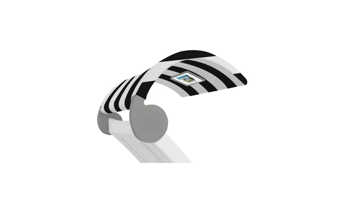 The Signature Chaise Shade by Ledge Lounger is a modern lamp with a flexible neck and black and white stripes. It features a sleek, white base with an on/off switch conveniently located on the shade.