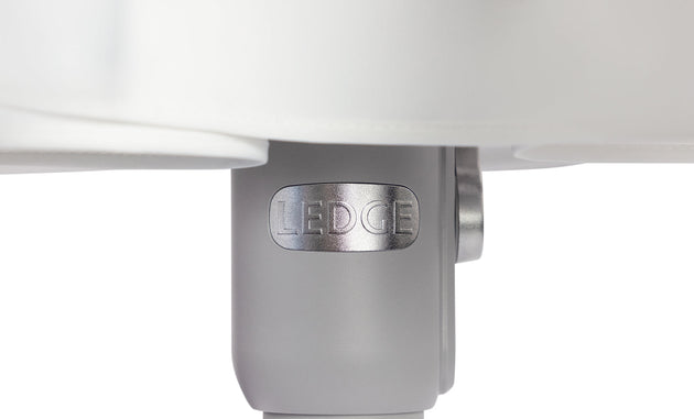 A close-up of a cylindrical metal component embossed with LEDCE evokes the durability of wind-resistant umbrellas. Connected to a larger white structure, it boasts a smooth light gray surface, reminiscent of the 6.5 Square Signature 360° Tilt Umbrella by Ledge Lounger.