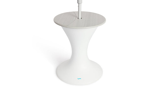 The Autograph Umbrella Stand Ice Bin by Ledge Lounger features a sleek design with a modern white pedestal base, a round gray top, and a central pole resembling an outdoor table. The flared base mimics an umbrella stand and showcases the small blue logo near the bottom.